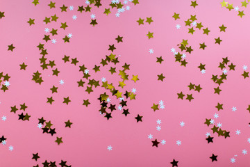 Stars and snowflakes on a pink background, from above