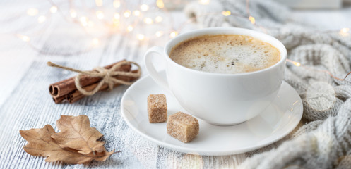 Cup of coffee, brown sugar, knitted scarf, garland. Autumn mood. Cozy autumn composition. Hygge...