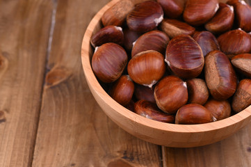 Cup of chestnuts on a wooden background. Autumn harvest and ripe fruits. Free space for text.