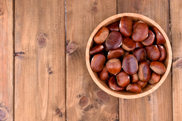 Cup of chestnuts on a wooden background. Autumn harvest and ripe fruits. Free space for text.