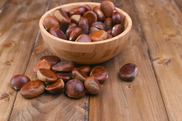 Cup of chestnuts on a wooden background. Autumn harvest and ripe fruits. Free space for text.