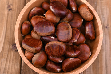Cup of chestnuts on a wooden background. Autumn harvest and ripe fruits. Free space for text.