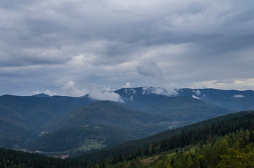 Naklejka na ściany i meble Mountain landscape with smoke fog and clouds over the rocks.