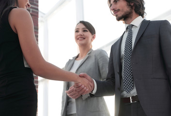 Businesspeople shaking hands against room with large window loo