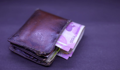 A brown leather wallet with money inside on the black background. Money concept, copy space for text.