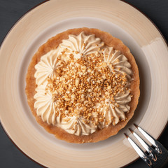 Cake basket with salted caramel on a checkered napkin near the dessert fork top view close-up.