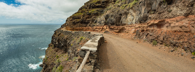 Narrow country road to the plateau of Punta Llana, where is the Ermita de Nuestra Senora de Guadalupe at La Gomera. Fisheye lens. Hiking trail descending to the coastal plateau. Canary Islands