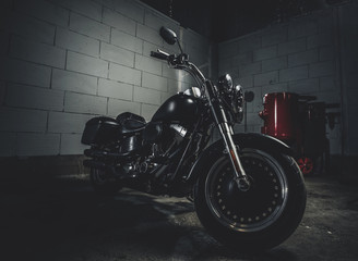 Beautiful shiny bike is parked in dark garage with white walls.