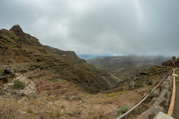 One of the tight turns of a narrow rural road in the mountains of Parque Natural Majona. View of the gorge and San Sebastian, the capital of the island of La Gomera. Canary Islands, Spain