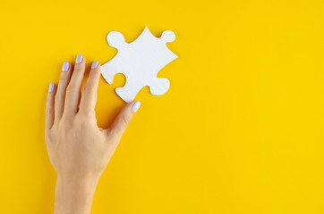 Hand with puzzles composition on yellow background.