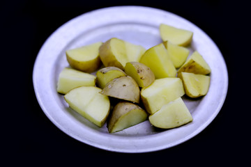 raw sliced potato of plate isolated on black background