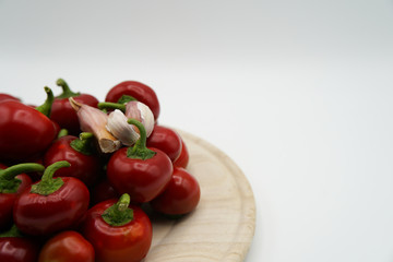 Side view of red hot chili peppers on wooden plate. Garlic and hot spicy vegetables. Fresh chili peppers and healthy food