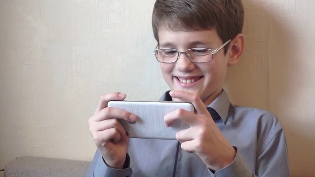 portrait of a boy in glasses sitting at a smartphone.schoolboy spends free time