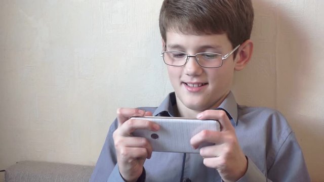 portrait of a boy in glasses sitting at a smartphone.schoolboy spends free time