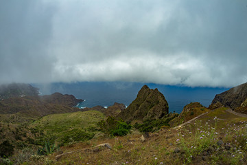 Narrow rural road in the mountains of Parque Natural Majona. Low wet clouds hanging over the green slopes. View of the north-eastern part of La Gomera island. Canary Islands, Spain