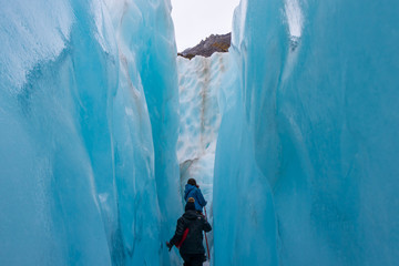 Two hikers in ice blue glacier crevasse on Franz Josef Glacier New Zealand