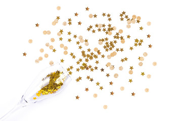 Top view of golden color confetti pouring from champagne glass isolated on white background. Festive party concept.