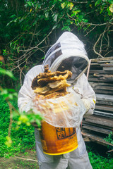 woman beekeeper holding a bucket of beeswax