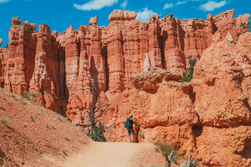 Fototapeta premium Hiker woman in Bryce Canyon hiking looking and enjoying view during her hike wearing hikers backpack. Bryce Canyon National Park landscape, Utah, United States. Sunny Day, clear skies, hot summer.