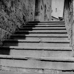 Fototapeta na wymiar An old staircase among the narrow streets in the medieval town of Massa Marittima in Tuscany shot with analogue film technique