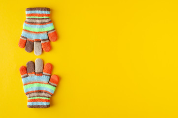 Striped kids winted gloves composition on yellow background.
