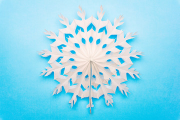 White snowflake (or sun) made of paper on a blue background. Christmas winter decorations