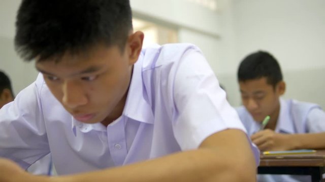  Rack focus shot of Asian high school students in white uniform are doing examinations.