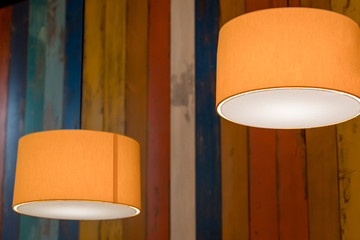 modern orange lamp with vintage light bulb.stylish lamps on wooden background.colorful wall,...