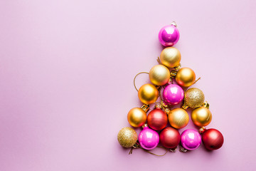 Christmas tree made of Christmas balls on pink background. Minimal styled New Year banner.