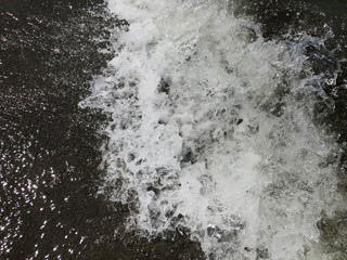 Close up of sea wave with splashes. Front view on beautiful sea wave on sandy beach. Summer sunny day, water background