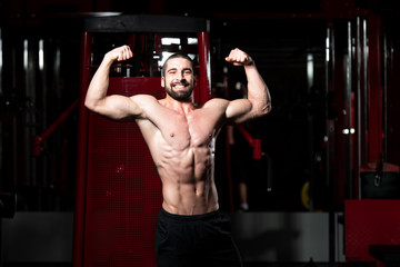 Biceps Pose Of A Young Man In Gym