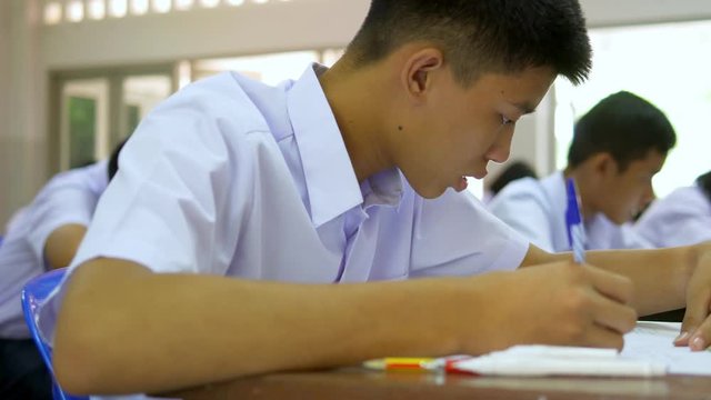  Rack focus shot of Asian high school students in white uniform are doing examinations.