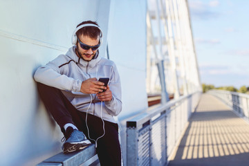 Portrait of young athlete man  preparing to exercise using smart-phone on sunny day