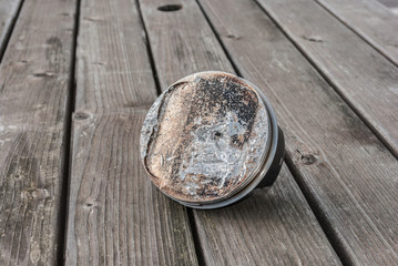 Broken and pitted  piston for motorbike showing severe damage resting on wooden table 
