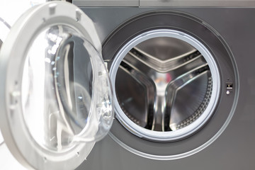 open glass door of a gray steel strip machine; drum of a washing machine. front view, close up