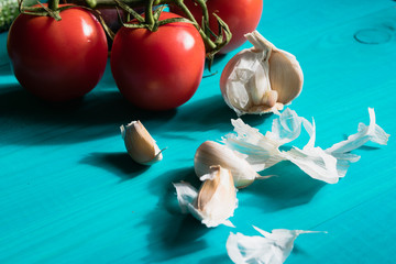 Organic ripe red tomatoes and garlic on a turquoise background. The concept of organic farming. Useful antioxidant vegetables.
