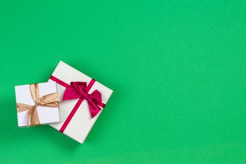 Two gift present boxes with ribbon on light green background, top view