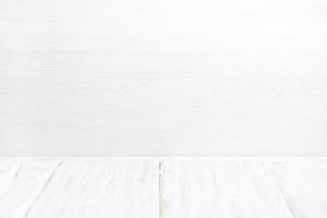 White wooden table top on white wall background.