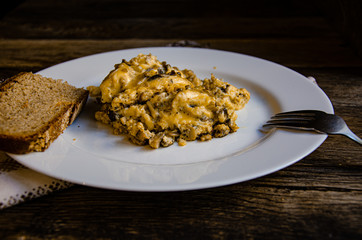 Omelet with mushrooms on a white plate on a wooden table.