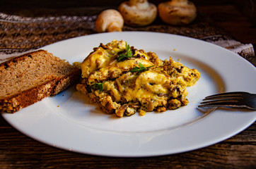 Omelet with mushrooms on a white plate on a wooden table.
