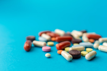 A scattered handful of colored pills on a blue background. Medical concept