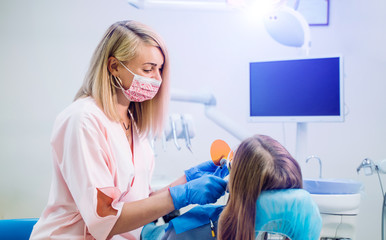 Attractive young woman in stomatology clinic with cheerful female dentist. Healthy teeth concept.