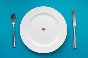 A small tablet in a plate. Medical concept. Eat pills instead of food.