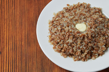 boiled buckwheat in a white plate on a wooden background