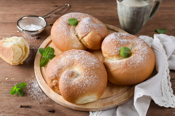 Buns with powdered sugar and milk on a wooden table