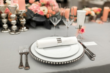 Part of stylish table setting with plate and cutlery. Nearby lies a white business card. Copy space