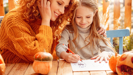 Mother and little daughter drawing spooky ghost for halloween