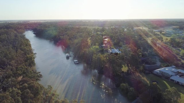 Aerial descend over Murray River facing the sun with lens flare. Echuca, Victoria, Australia