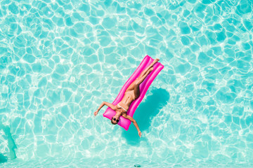 Summer Vacation. Enjoying suntan woman in bikini on the inflatable mattress in the swimming pool.
