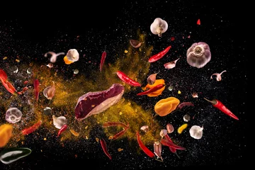 Poster Im Rahmen Scharfe rote Paprika, Knoblauch, verschiedene Gewürze Pulver Fleischpfähle fliegen auf schwarzem Hintergrund Motion Freeze Fotokomposition © Vitte Yevhen